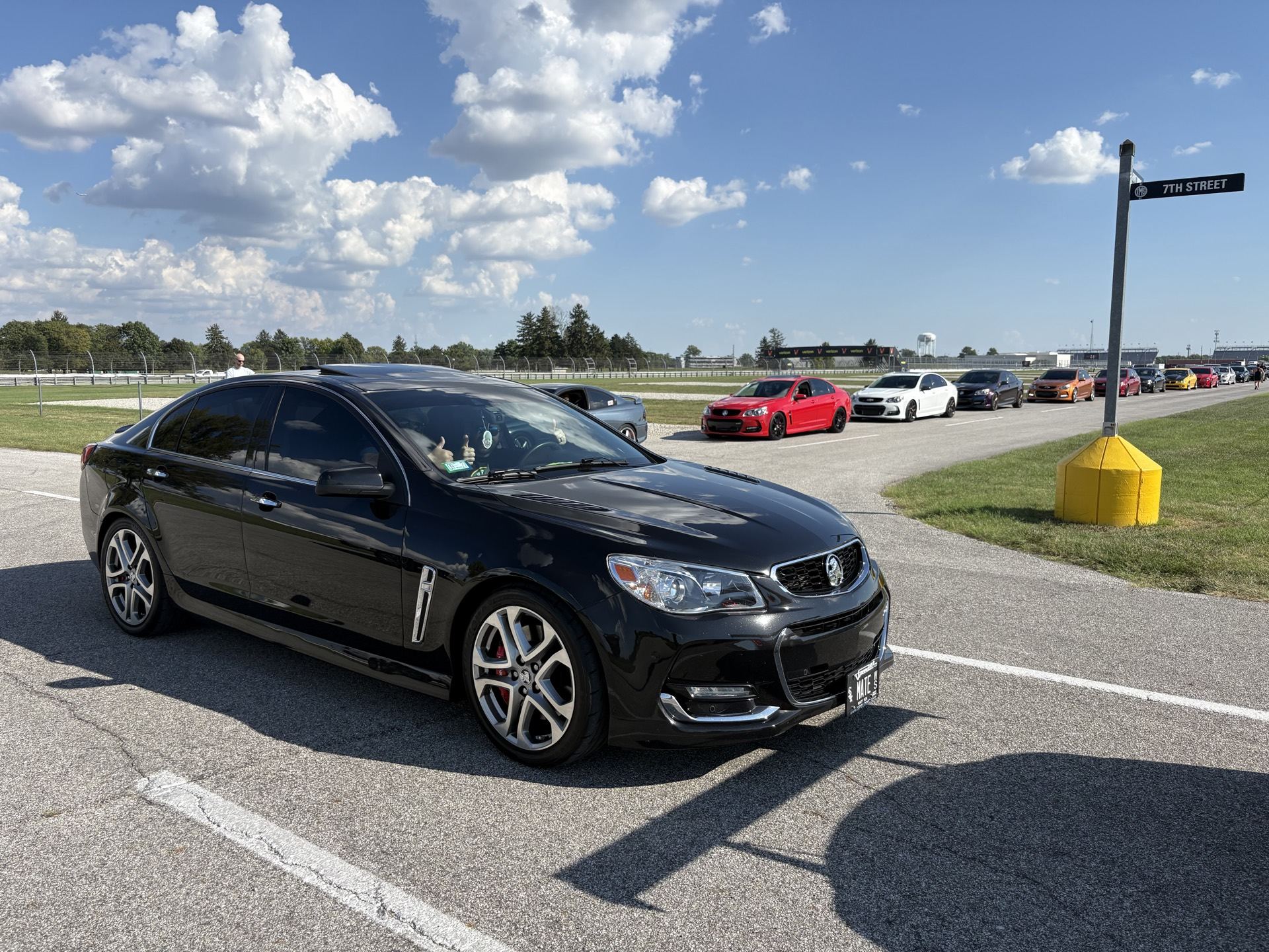 Chevy SS driving past other attendees and a directional sign at the venue